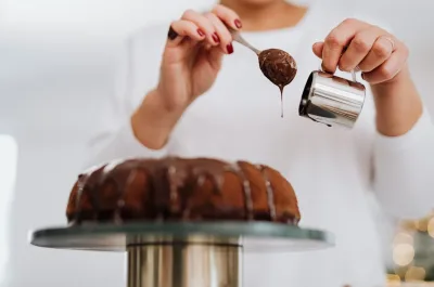 Pastel de chocolate al que se le está echando más chocolate por encima.
